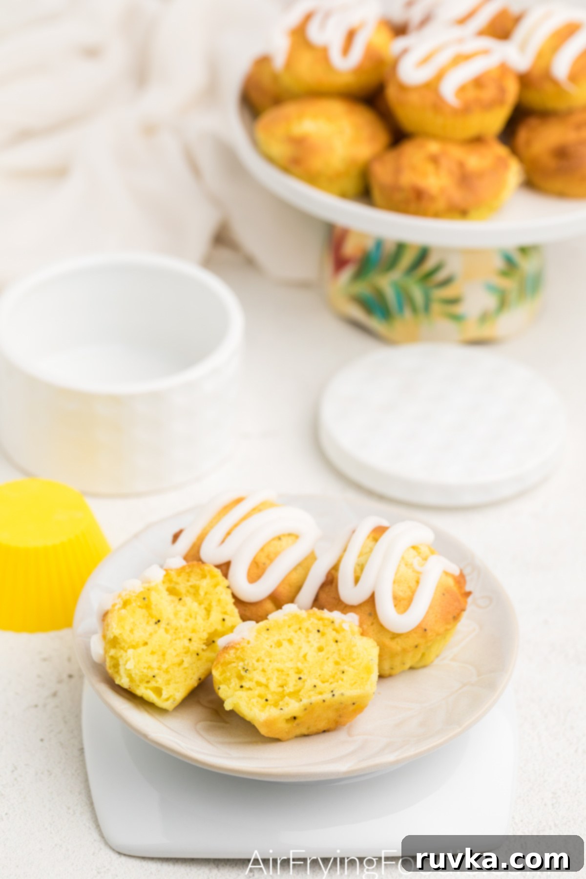 Zesty Air Fryer Lemon Poppy Seed Muffins 9 Air fryer lemon poppy seed muffins on a plate with one sliced in half.