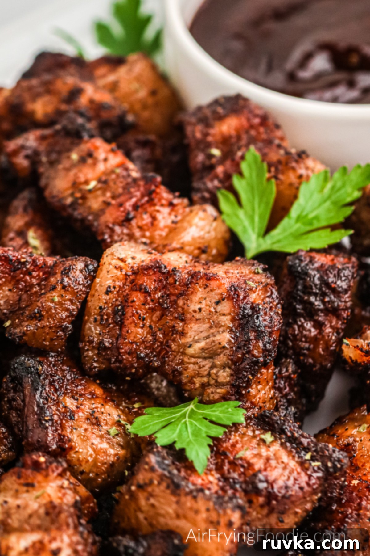 Air Fried Pork Belly Perfection 6 Seasoned and crispy air fryer pork belly on a serving platter with fresh parsley and BBQ dipping sauce.