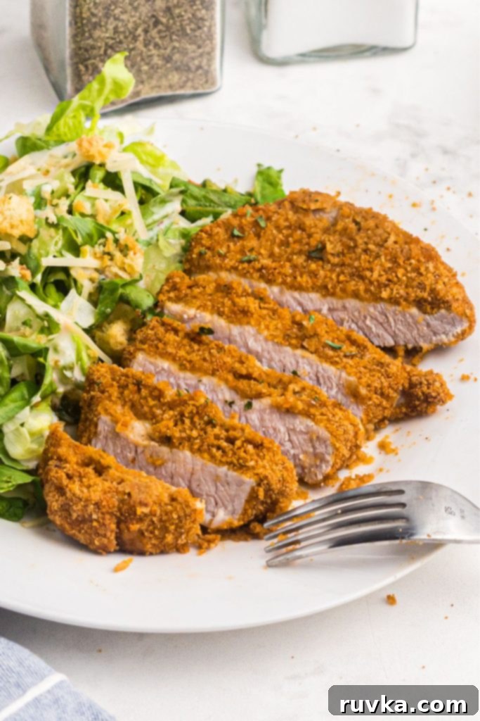 Crispy Air Fryer Pork Chops 2 Golden crispy pork chops sliced and served on a white plate with salad