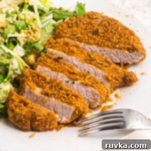 Crispy Air Fryer Pork Chops 9 Golden crispy pork chop sliced on a white plate with salad and a fork