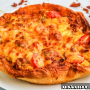 Crispy Air Fryer Breakfast Pizza 7 Breakfast pizza on a white plate ready to slice and serve.