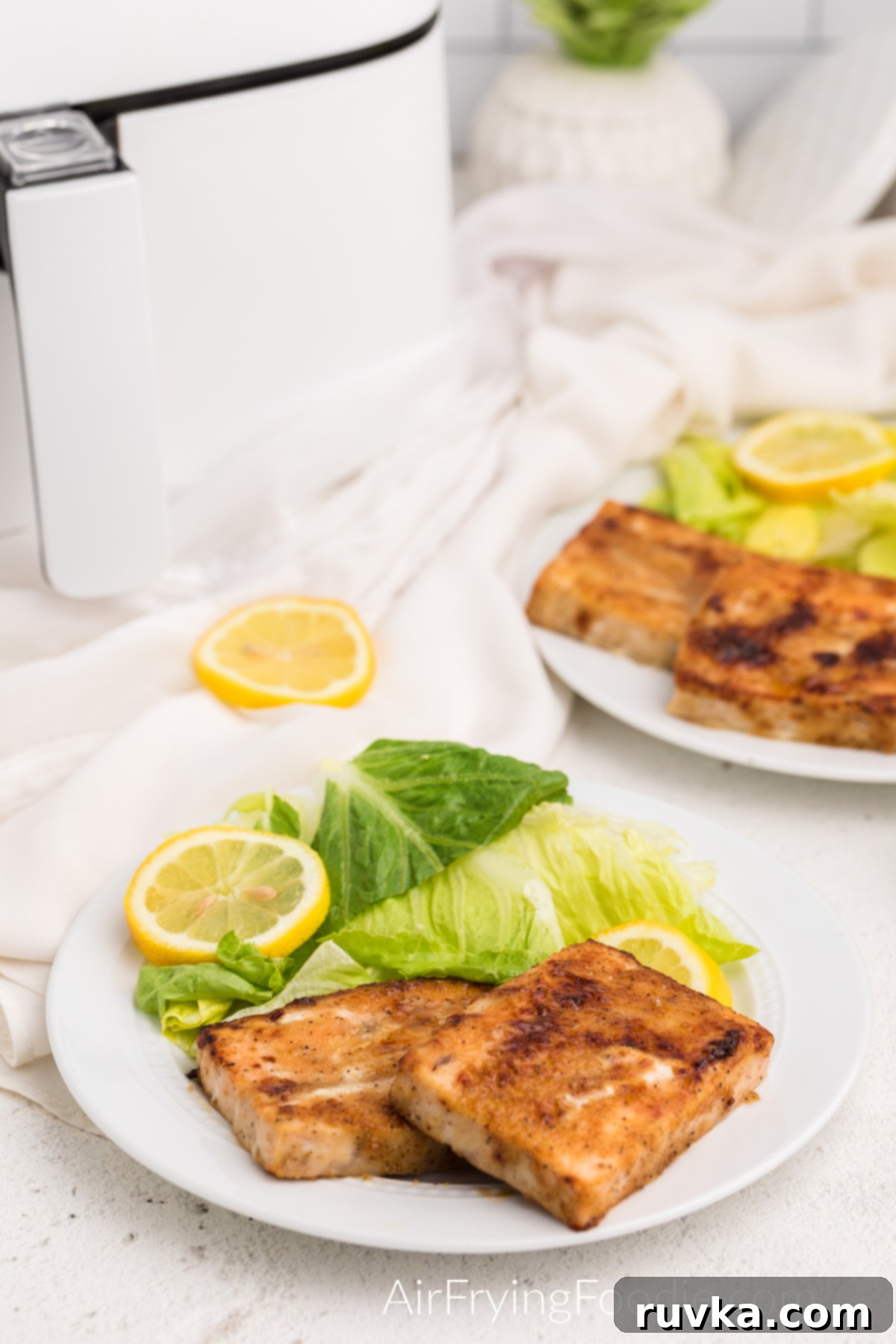 Perfect Air Fryer Frozen Salmon 2 Seasoned and cooked air fryer frozen salmon on a white plate with a fresh salad and lemon slices, ready to serve.