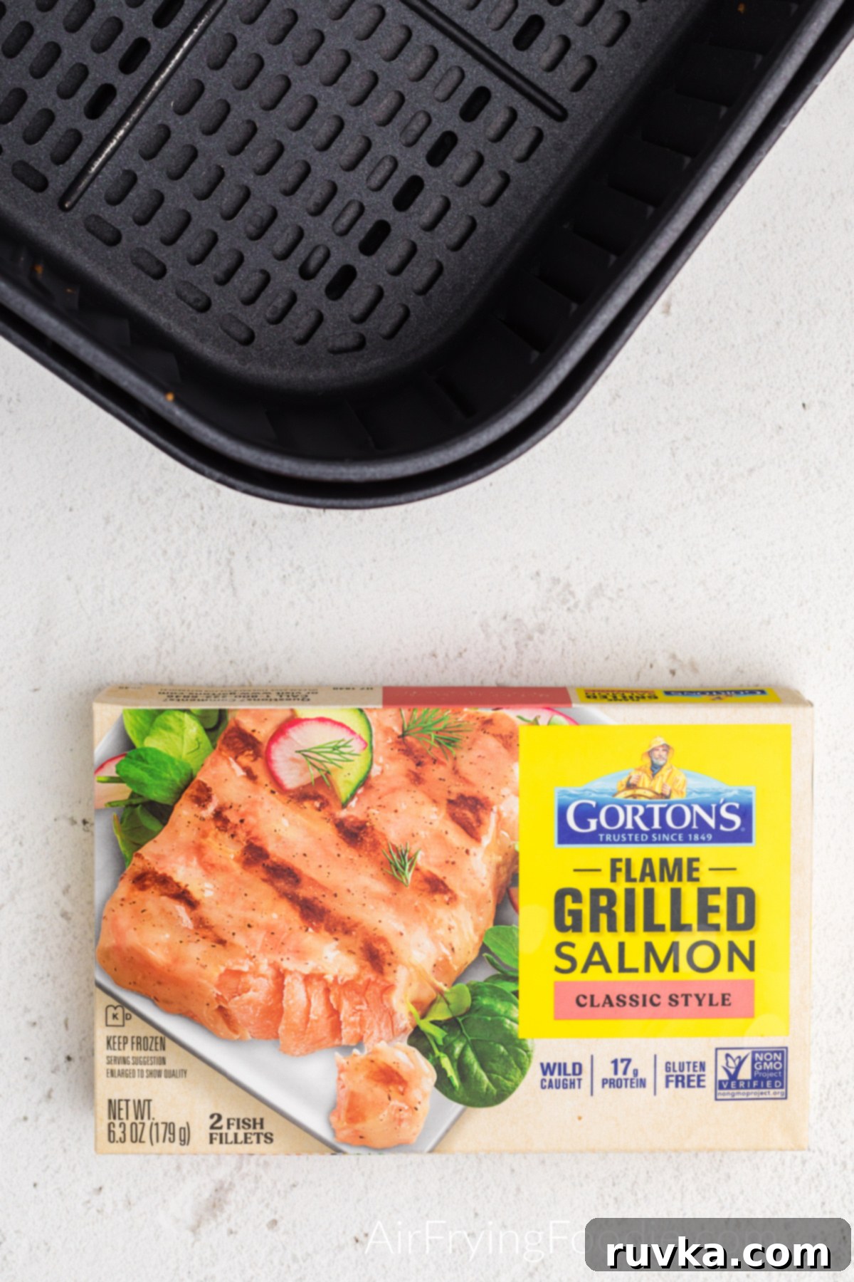 Perfect Air Fryer Frozen Salmon 3 Air fryer basket next to Gorton's flame-grilled frozen salmon fillets, ready for cooking.