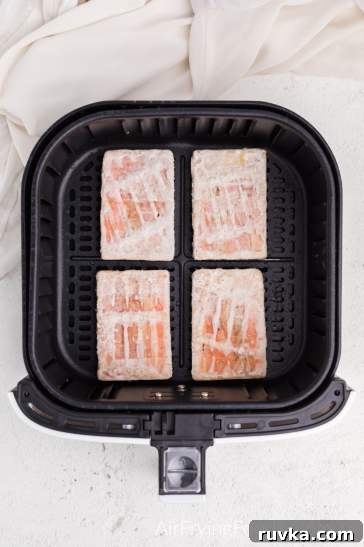 Perfect Air Fryer Frozen Salmon 4 Frozen salmon fillets placed in an air fryer basket, ready for the initial cooking phase to defrost.