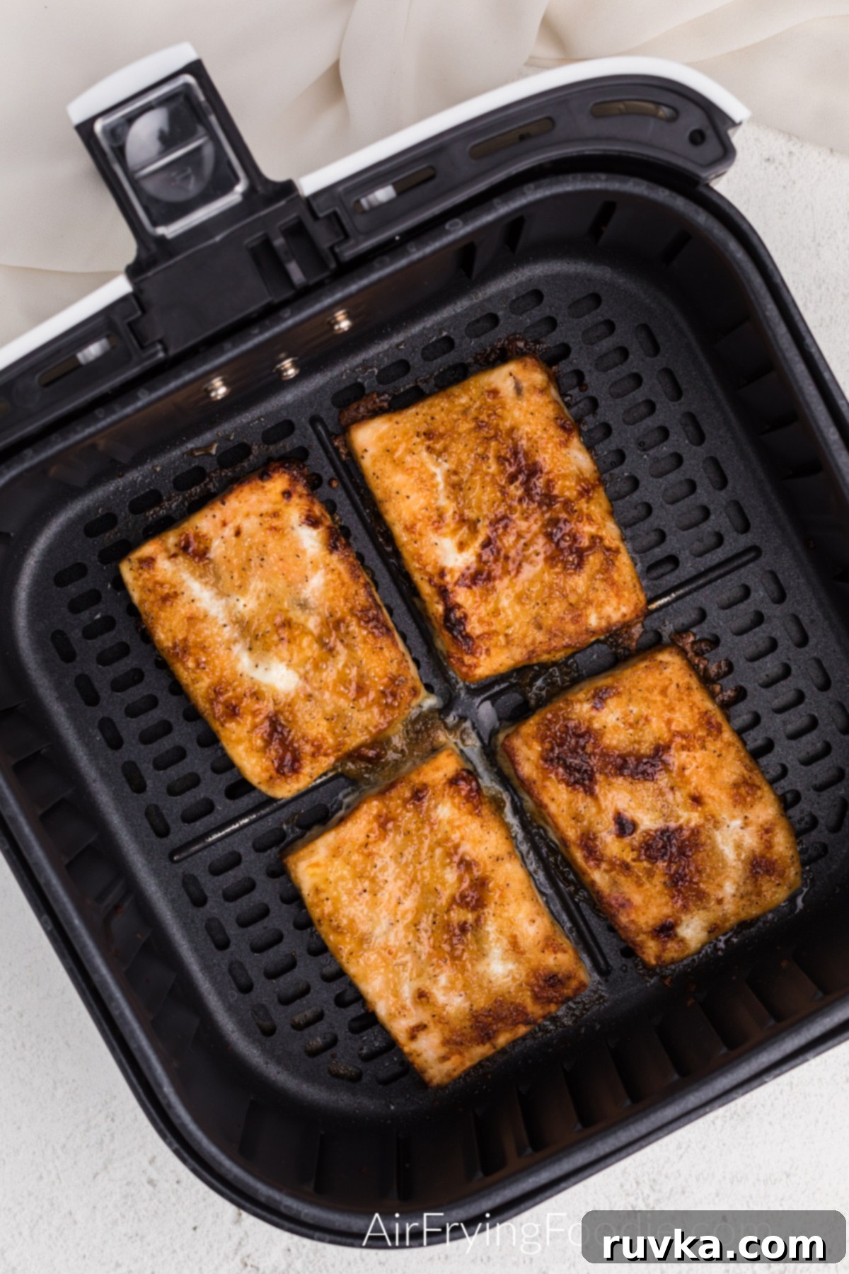 Perfect Air Fryer Frozen Salmon 6 Perfectly cooked air fryer frozen salmon, golden brown and flaky, resting in the air fryer basket ready to be served.