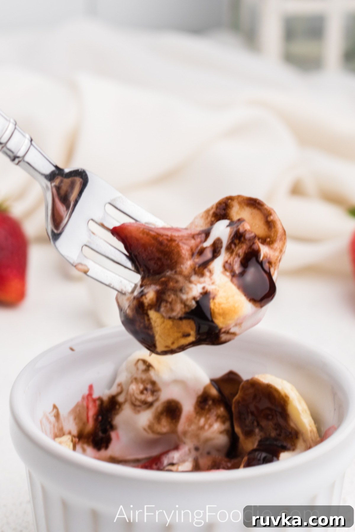 Delicious Air Fryer Strawberry Banana Bowl 7 Close up bite shot of air fried strawberry, banana, and marshmallow with chocolate topping, showing gooey texture.