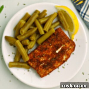Quick and Delicious Air Fryer Mahi Mahi 5 Overhead photo of air fried Mahi Mahi on a white plate with green beans and a lemon slice.