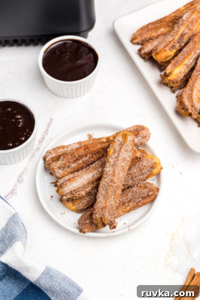 Crispy Air Fryer Churros 2 Golden sugar and cinnamon coated churros on a white plate with chocolate sauce