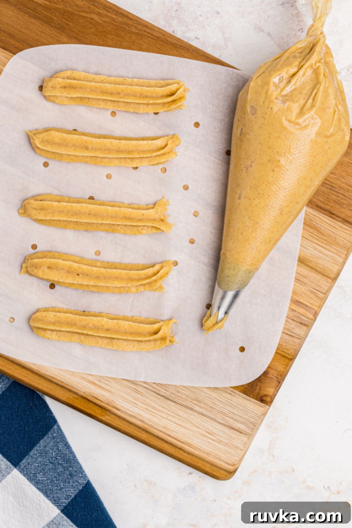 Crispy Air Fryer Churros 6 Churro dough in a piping bag after piping churros on parchment paper