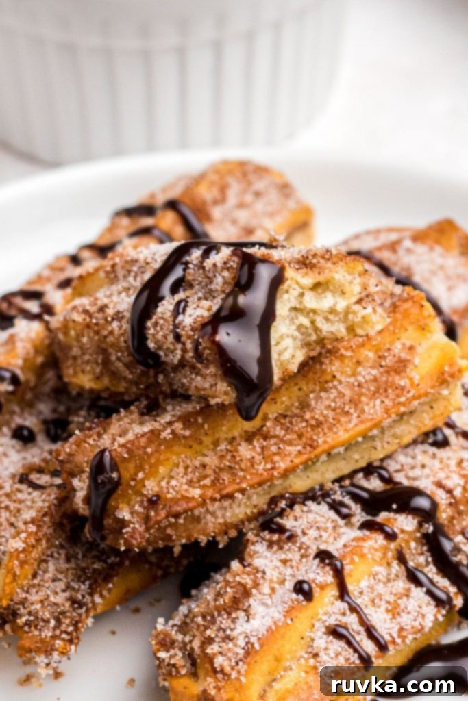 Crispy Air Fryer Churros 9 Golden crispy churros on a white plate with melted chocolate dip