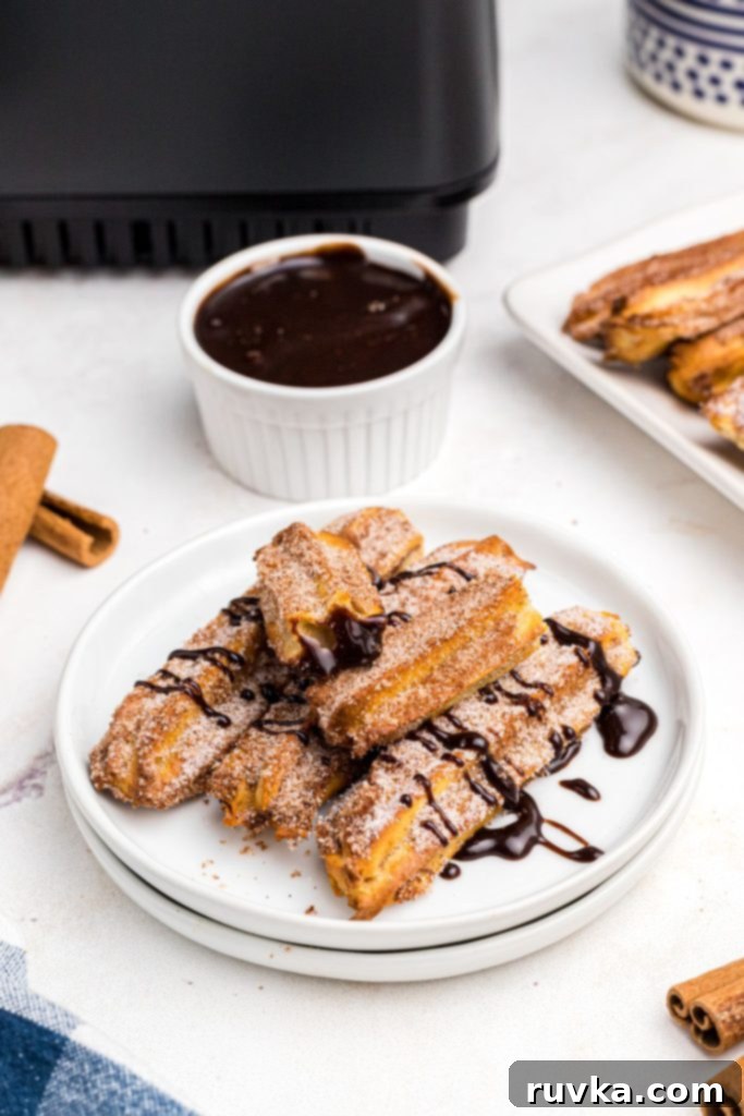 Crispy Air Fryer Churros 10 Golden crispy sugar coated churros on a white plate then drizzled in chocolate