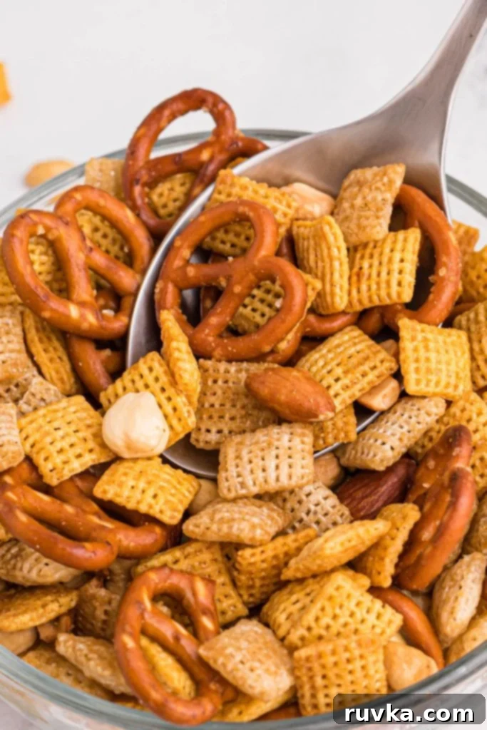 Easy Air Fryer Chex Mix 2 Air fryer chex mix on a spoon being scooped out of a clear bowl