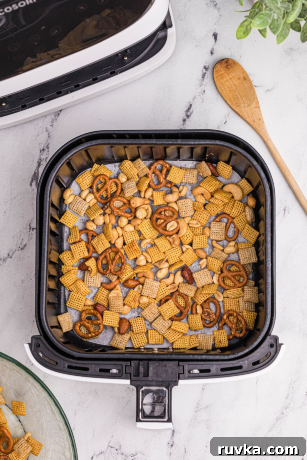 Easy Air Fryer Chex Mix 7 Air fryer chex mix being added to the basket before being cooked