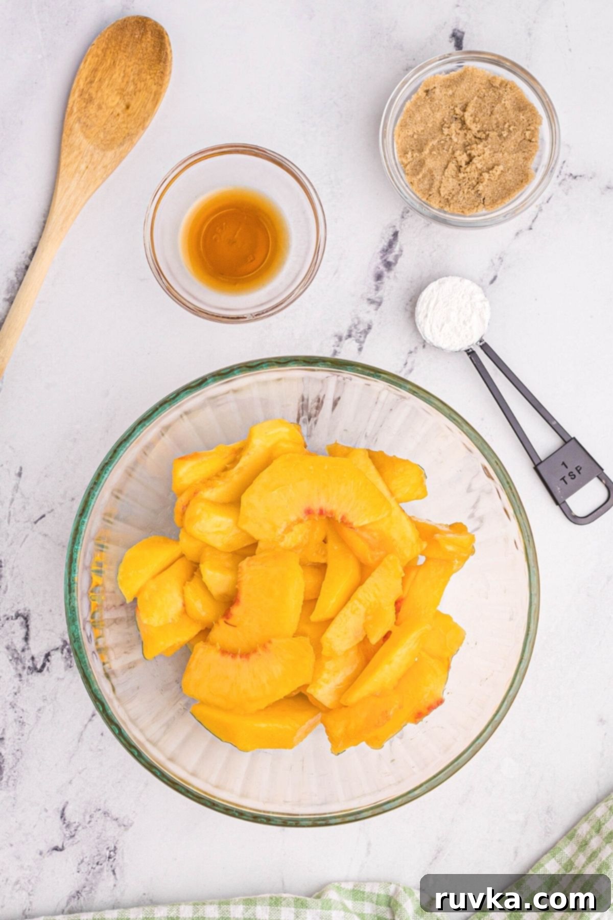 Easy Air Fryer Peach Cobbler 5 Peaches in glass bowl with seasonings for cobbler filling measured around the bowl