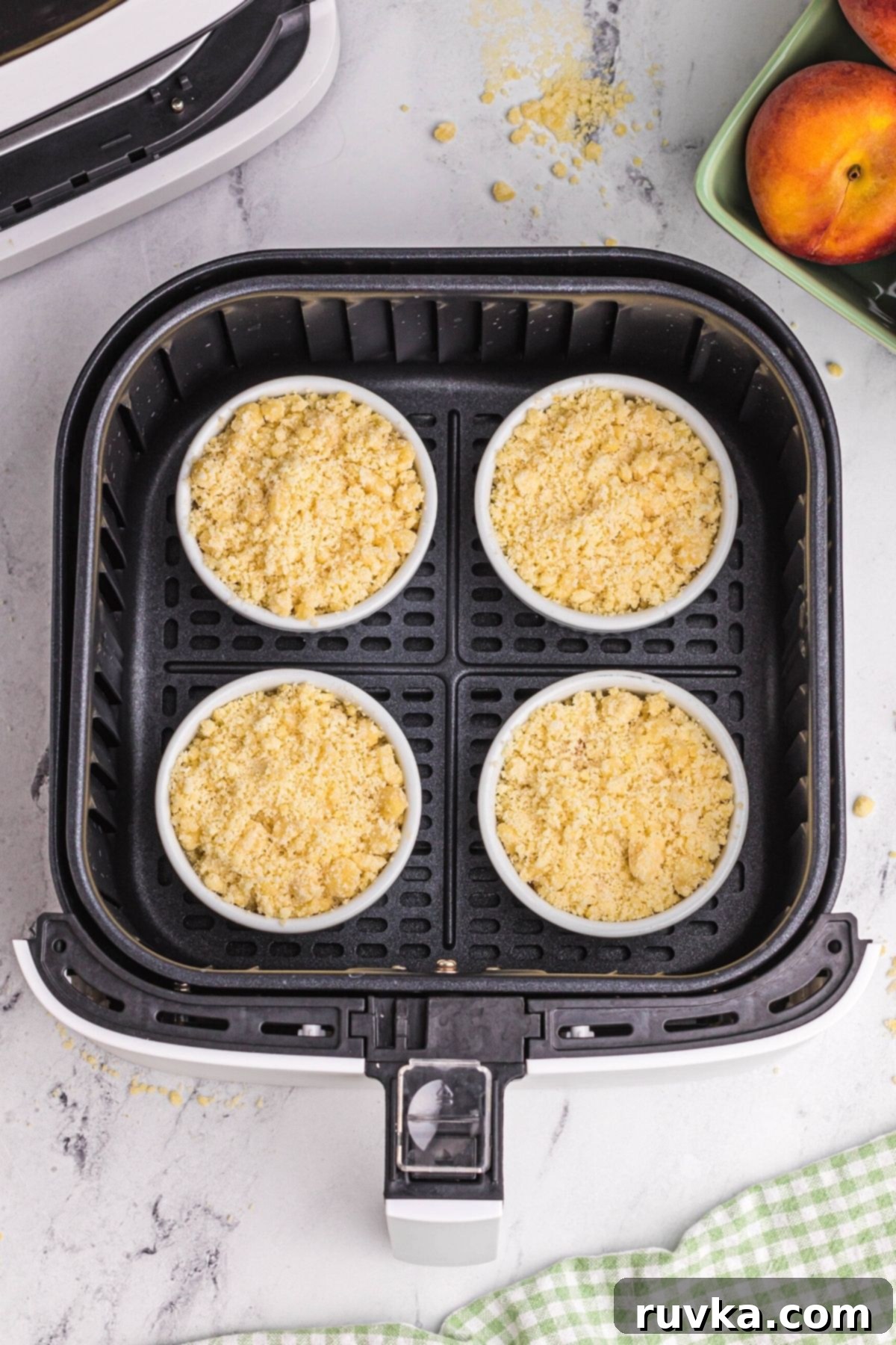 Easy Air Fryer Peach Cobbler 7 Peach cobblers in ramekins in an air fryer basket