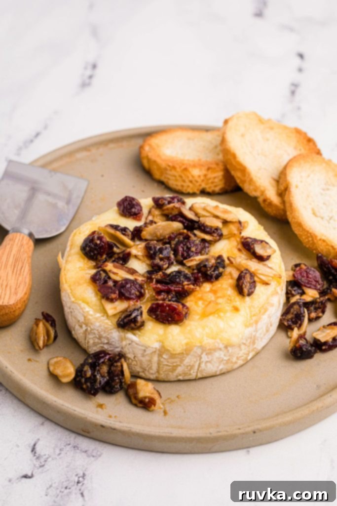 Golden Air Fried Brie 2 Wheel of brie cheese with nuts and berry toppings and toasted bread served on a tray, highlighting a perfect air fryer brie appetizer.