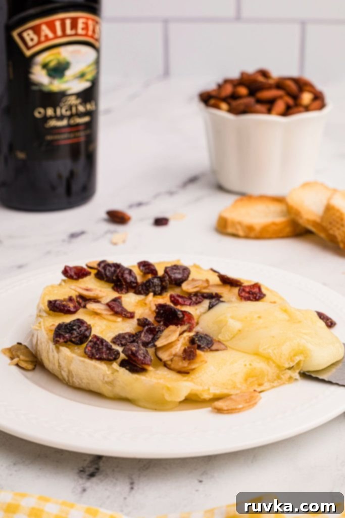 Golden Air Fried Brie 8 Melted brie cheese on a white plate, beautifully topped with berries and nuts, ready to be enjoyed as a gourmet appetizer.