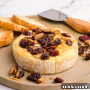 Golden Air Fried Brie 9 Wheel of brie cheese on a serving dish with nuts and berries and slices of bread on a platter. A perfect Air Fryer Brie appetizer.