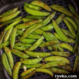Crispy Air-Fried Snap Peas 10 Juicy green snap peas in the air fryer basket after being cooked to perfection.