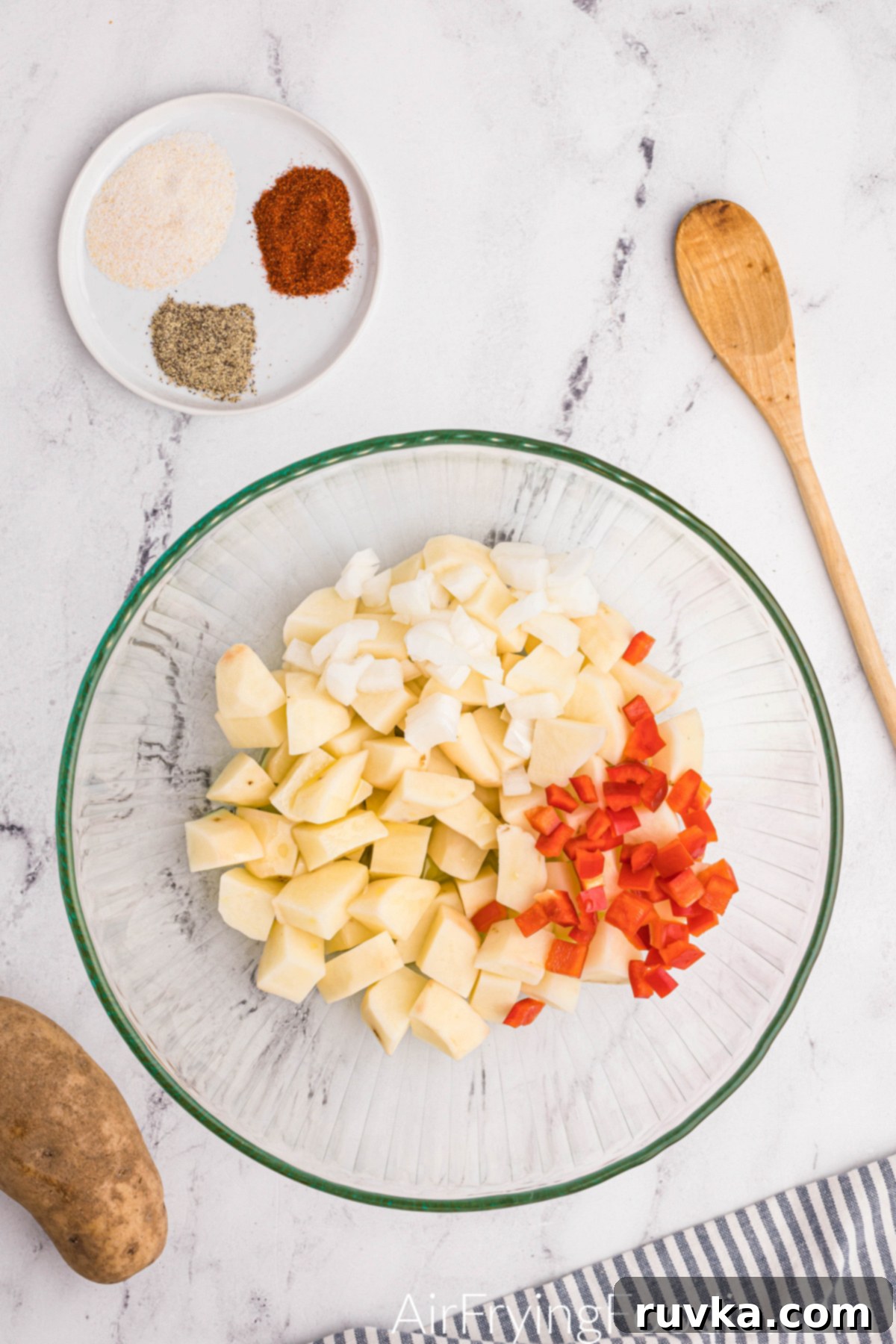 Crispy Air Fryer Home Fries 5 Bell pepper and onion added to a bowl of freshly cut russet potatoes, ready for seasoning.