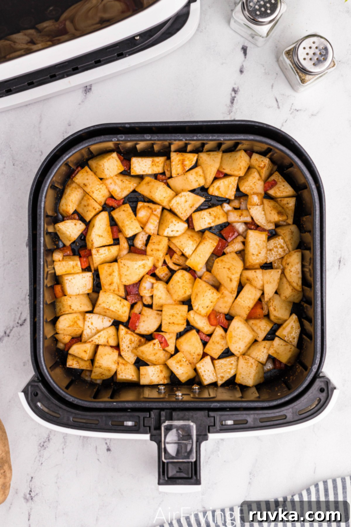 Crispy Air Fryer Home Fries 7 Diced potatoes, seasoned and mixed with bell pepper and onion, arranged in a single layer in the air fryer basket.