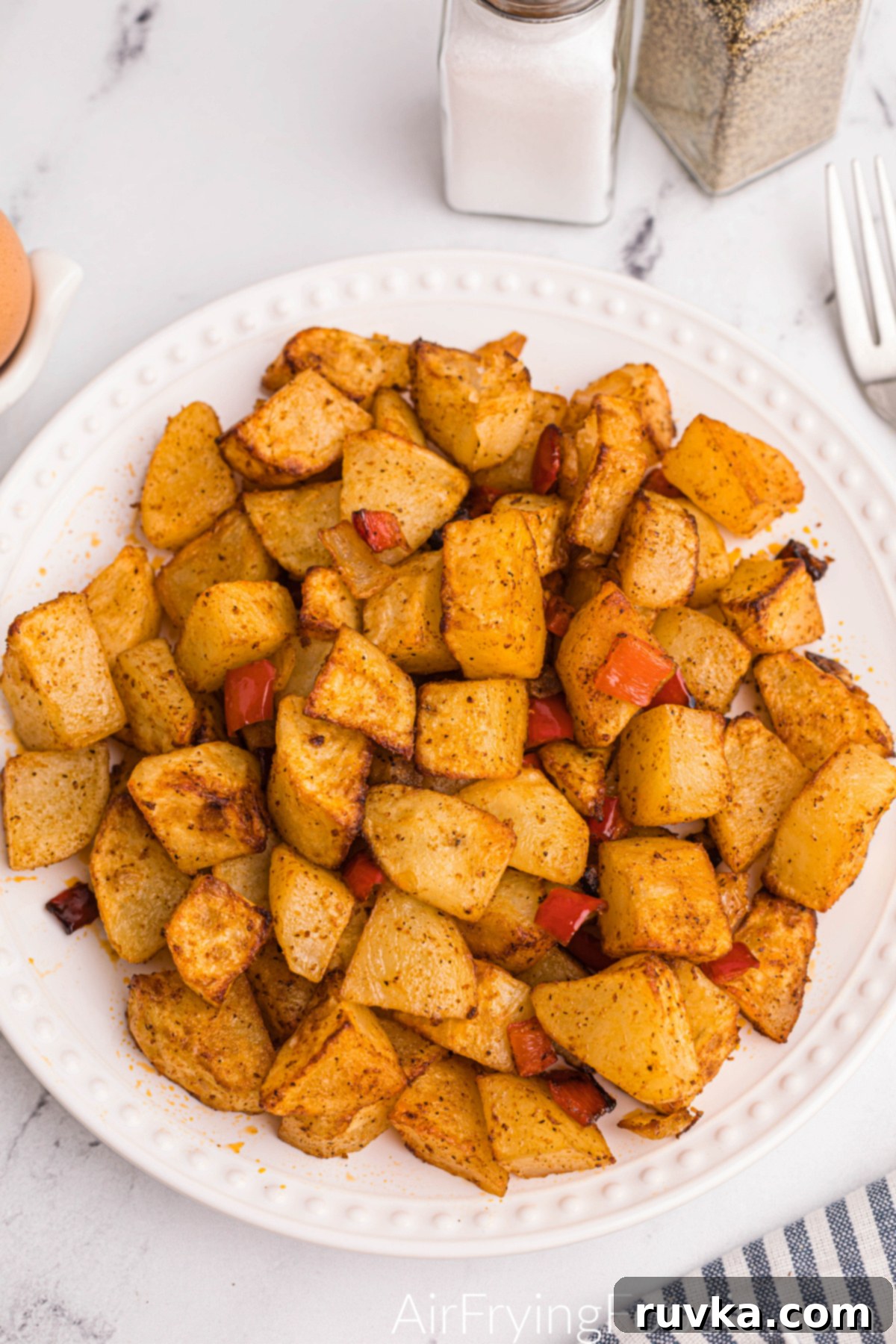 Crispy Air Fryer Home Fries 9 Air fried home fries on a pristine white plate, garnished with fresh parsley, ready to be enjoyed.