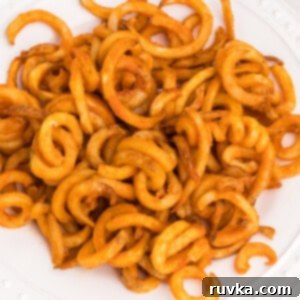 Student Air Fryer Survival Guide 11 Air fried frozen curly fries on a white plate, seasoned and ready to eat, showing their perfect crispy texture.