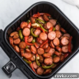 Student Air Fryer Survival Guide 3 Sausage and peppers in an Air Fryer basket, perfectly cooked and vibrant.
