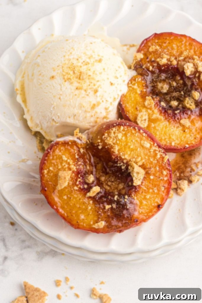 Golden Air-Fried Peaches 2 Juicy air fried peaches on a white plate served with a scoop of ice cream and topped with graham cracker crumbs