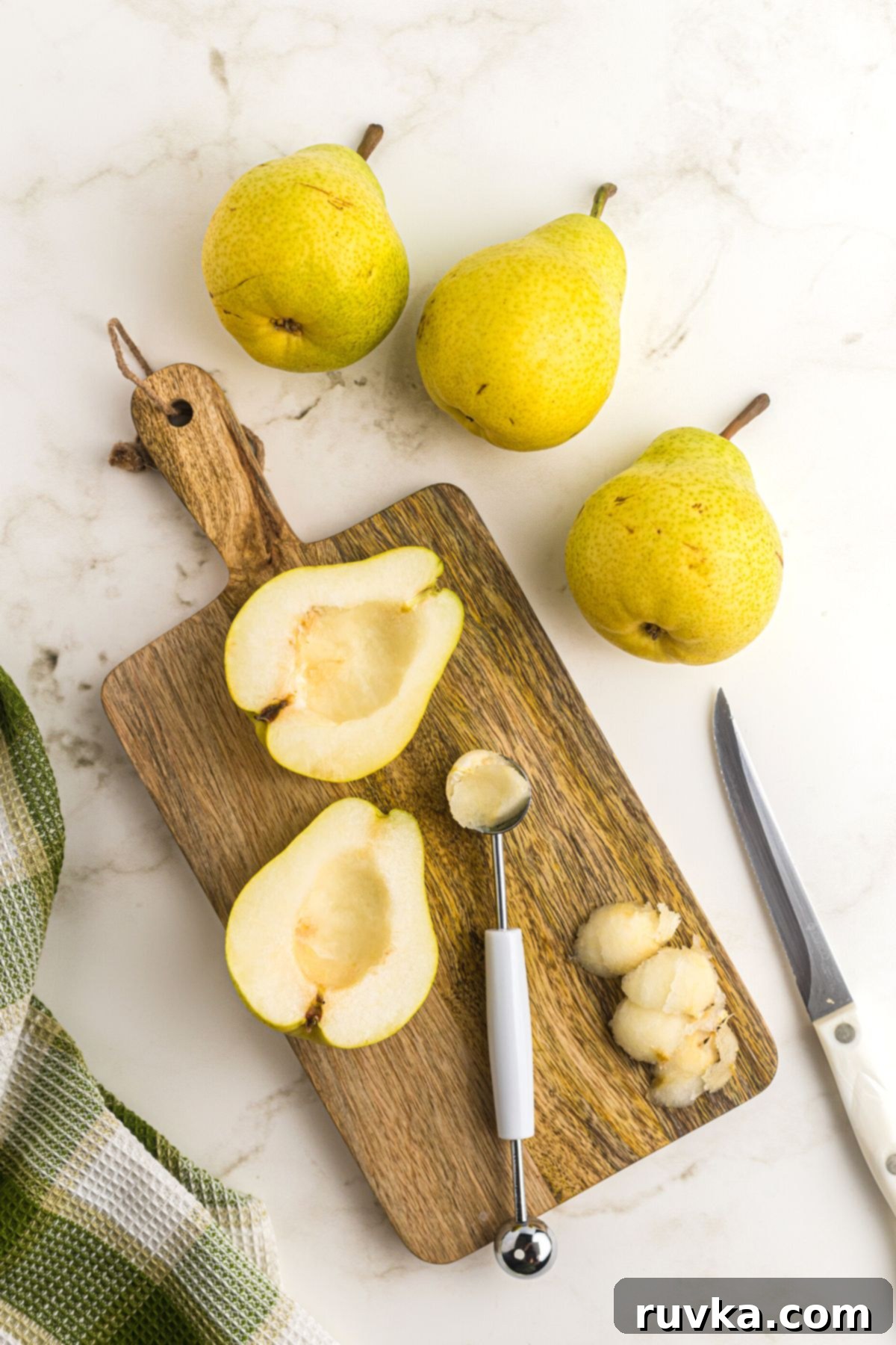 Golden Air Fryer Pears 4 pears on a wooden cutting board sliced in half and cored