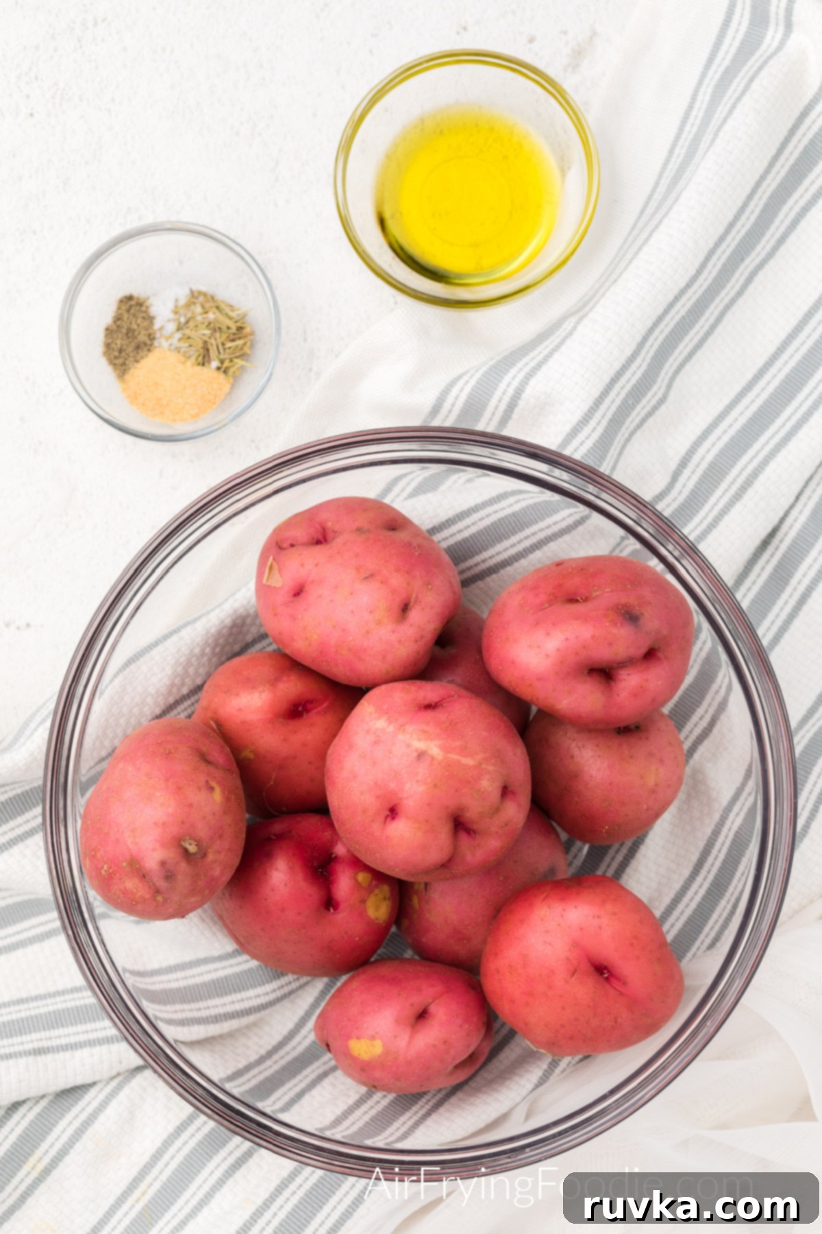 Crispy Air Fryer Red Potatoes 3 Ingredients for air fryer red potatoes. baby red potatoes in a dish, seasonings in a dish, and olive oil in a dish.