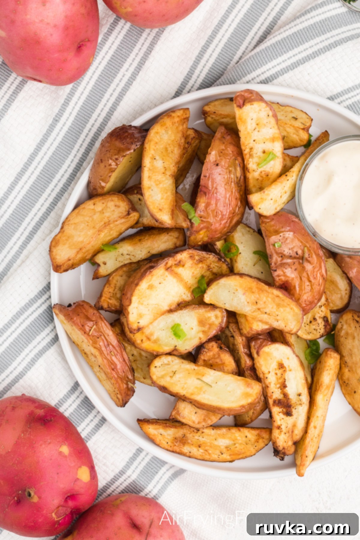 Crispy Air Fryer Red Potatoes 7 Seasoned air fried red potatoes on a white plate with dipping sauce.