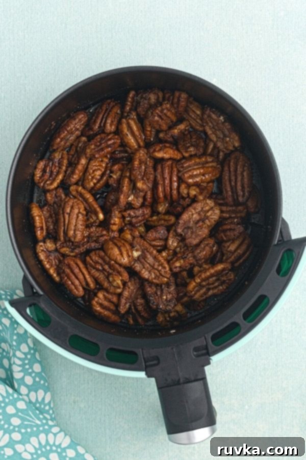 Irresistible Air Fryer Spiced Pecans 5 Spiced air fryer pecans, after being cooked in the air fryer, resting in the air fryer basket.