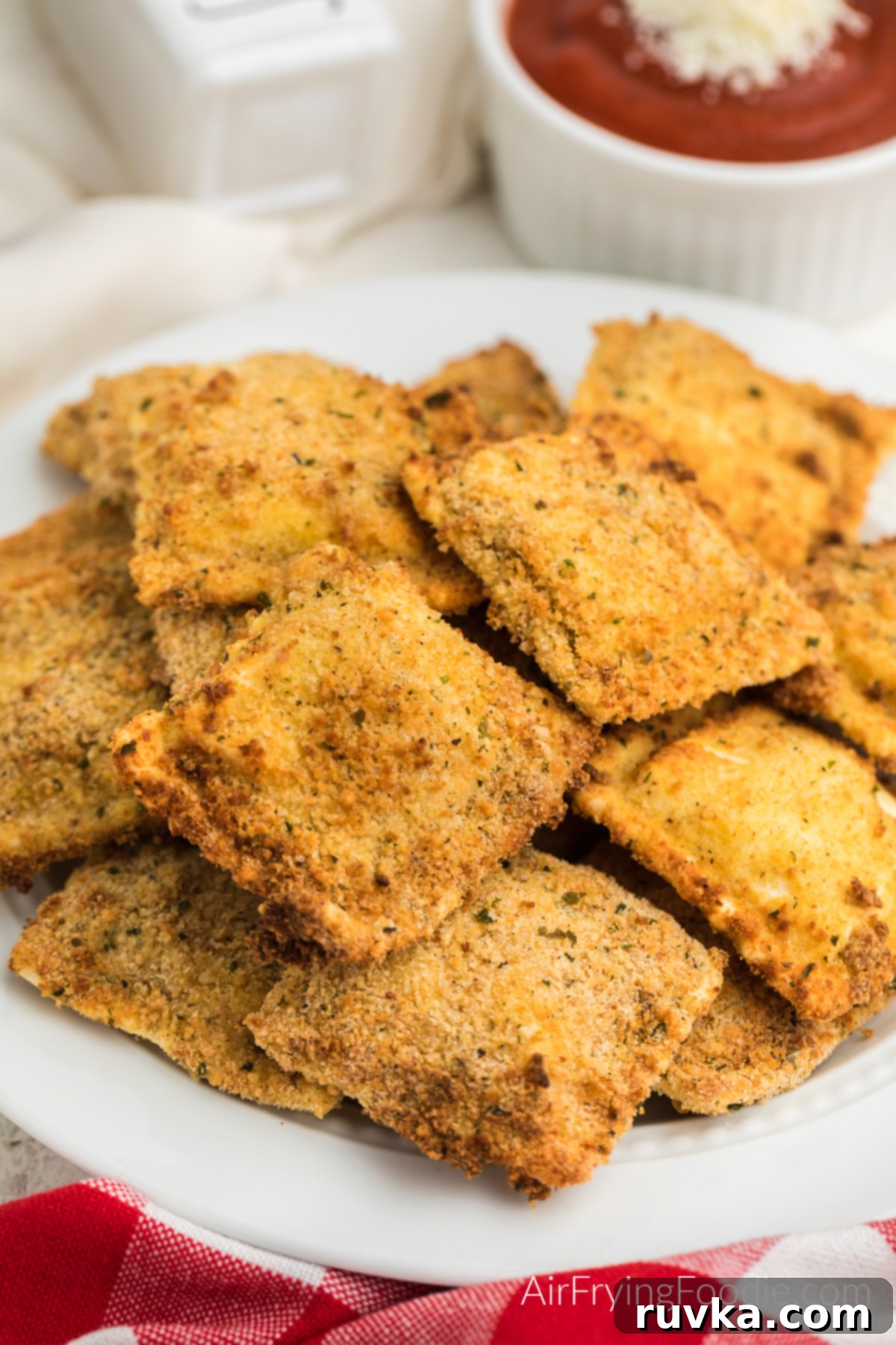 Golden Air-Fried Ravioli Bites 2 Fried Ravioli made in the air fryer, served on a white plate. Ready to eat.