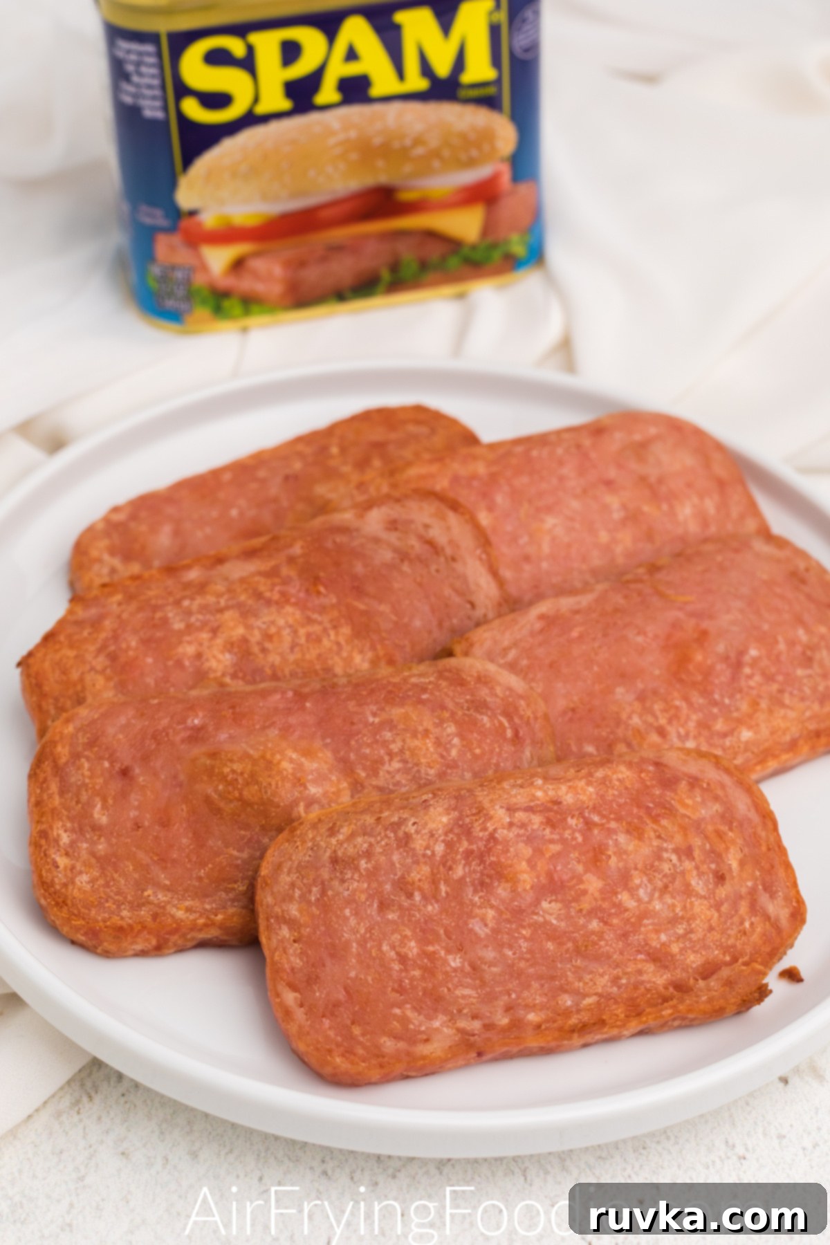 Crispy Air-Fried Spam 2 Slices of cooked Spam made in the air fryer and served on a white plate.