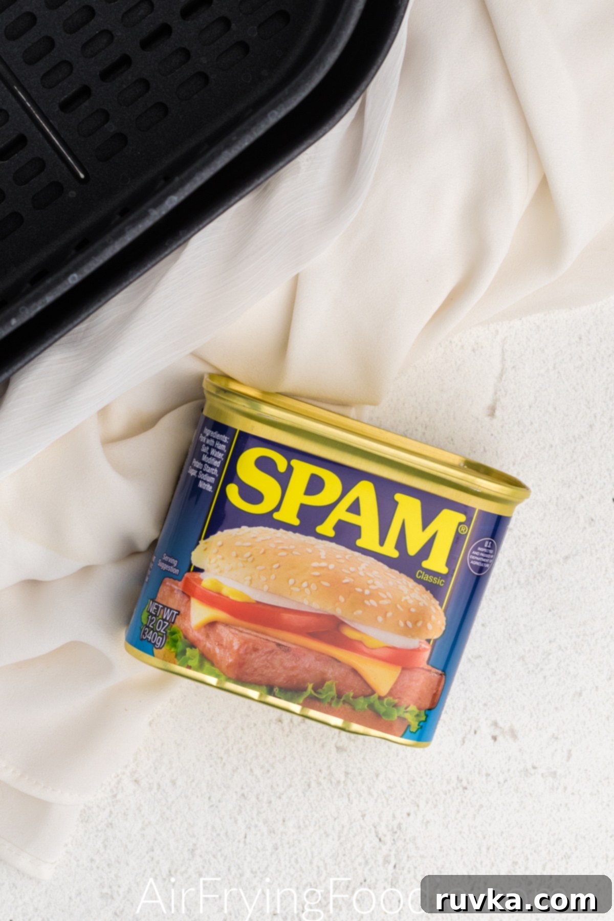Crispy Air-Fried Spam 3 Can of classic Spam and the basket of the air fryer on a white table.