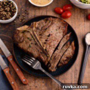Restaurant-Quality Air Fryer T-Bone 9 Juicy T-Bone steak on a blue plate with sauce, fork, and knives on the table, cooked in an air fryer.