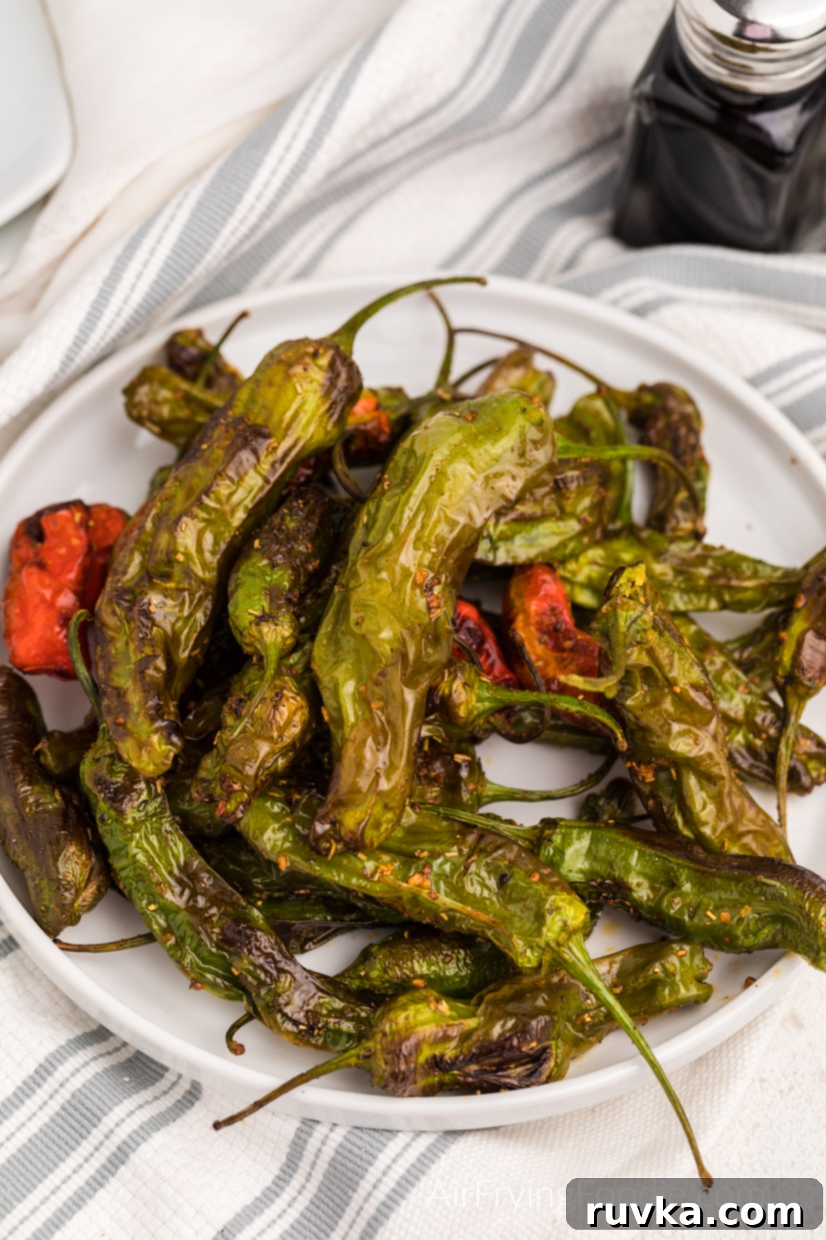 Crispy Air Fryer Shishito Peppers 2 Air fried shishito peppers on a white plate ready to serve.
