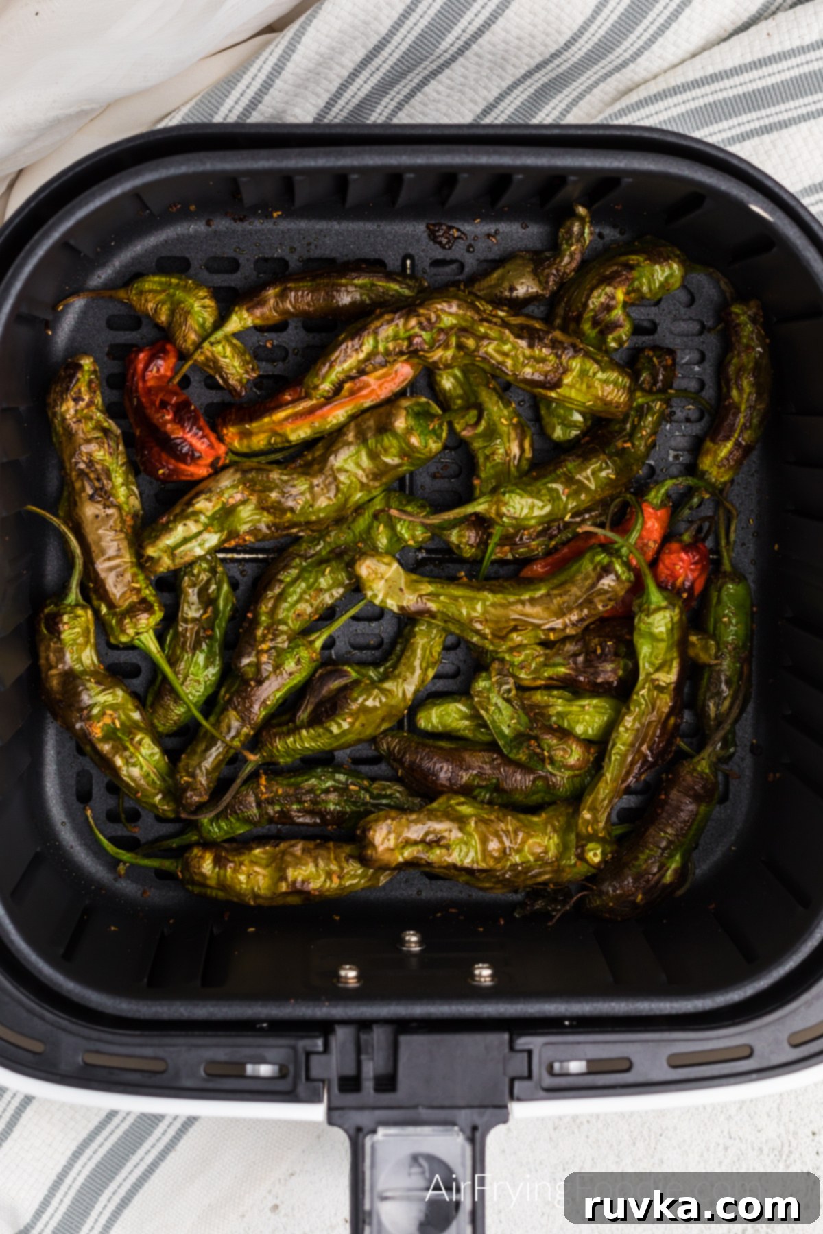 Crispy Air Fryer Shishito Peppers 5 Air fried shishito peppers in the basket of the air fryer.