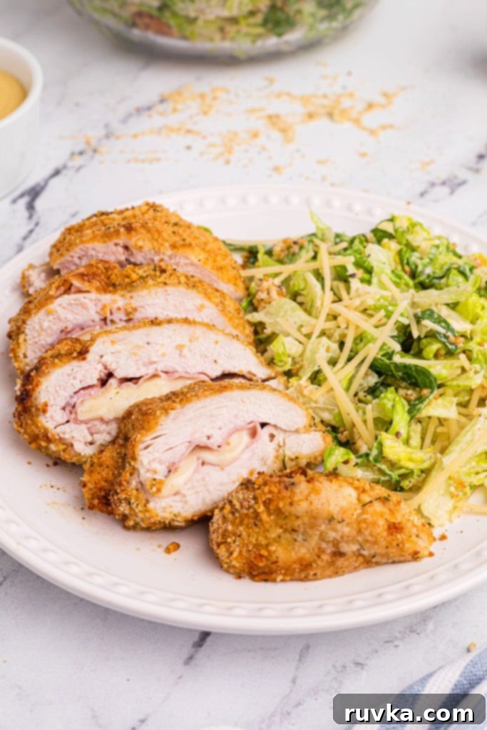 Crispy Air Fryer Chicken Cordon Bleu 2 Golden crispy chicken stuffed with cheese and ham served on a white plate
