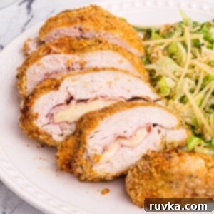 Crispy Air Fryer Chicken Cordon Bleu 12 Golden crispy coated chicken sliced and filled with ham and cheese on a white plate