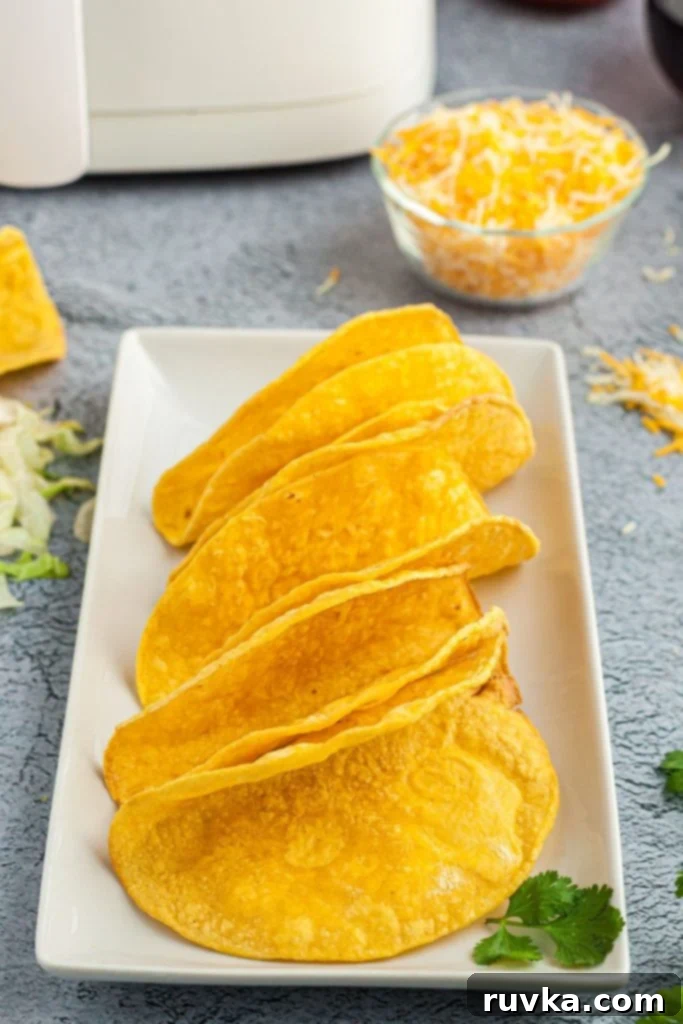 Easy Crispy Air Fryer Taco Shells 2 golden crispy air fried taco shells on a white plate