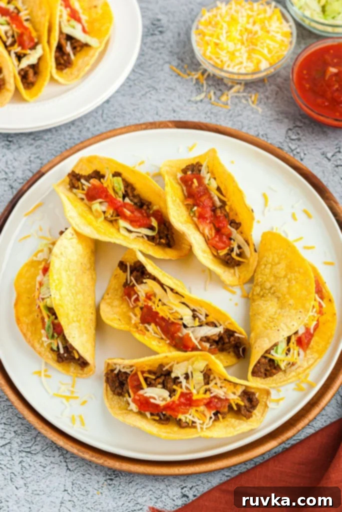 Easy Crispy Air Fryer Taco Shells 7 crispy taco shells filled with taco fillings on a white plate