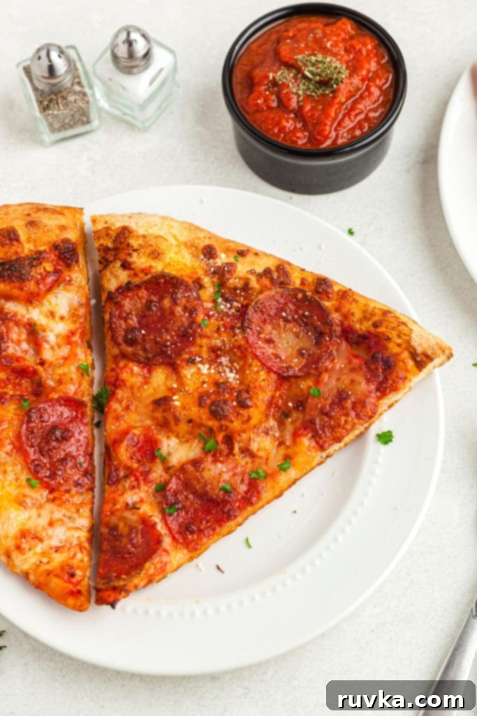 Air Fryer Magic: Crispy Leftover Pizza Every Time 2 Golden cheesy pizza on a white plate in front of dipping sauce.