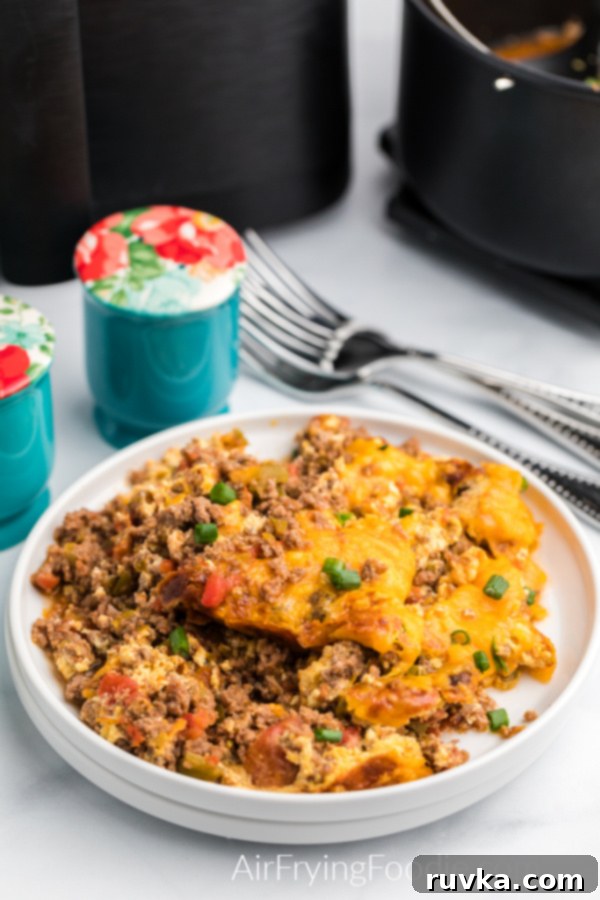 Crispy Air Fryer Taco Bake 3 Taco casserole made in the airfryer, garnished with green onion tops, and served on a white plate.