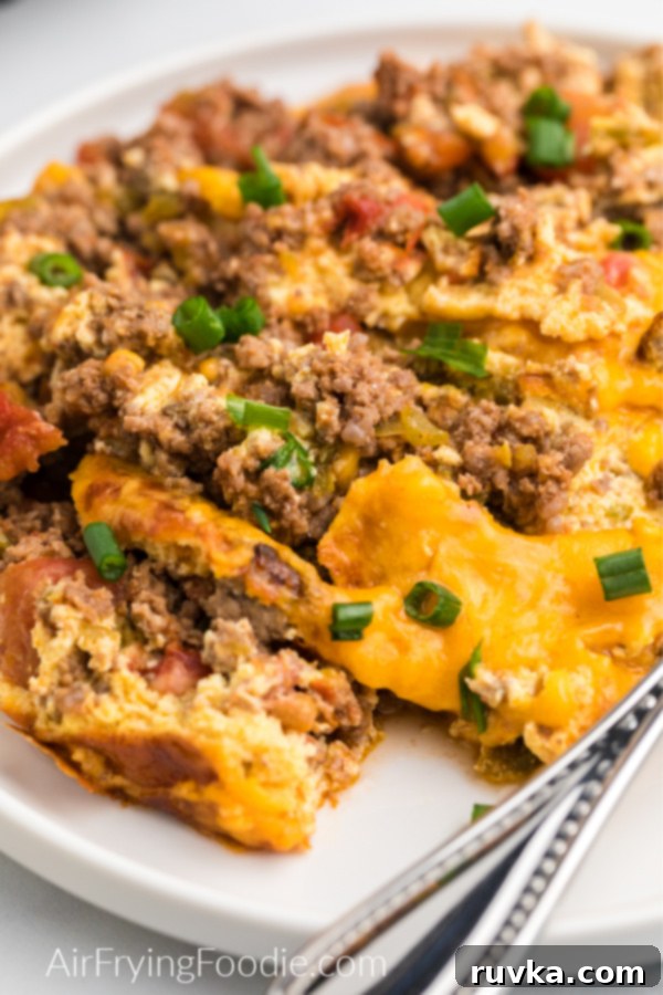 Crispy Air Fryer Taco Bake 6 Close up photo of air fryer keto friendly taco casserole garnished with green onions and served on a white plate.