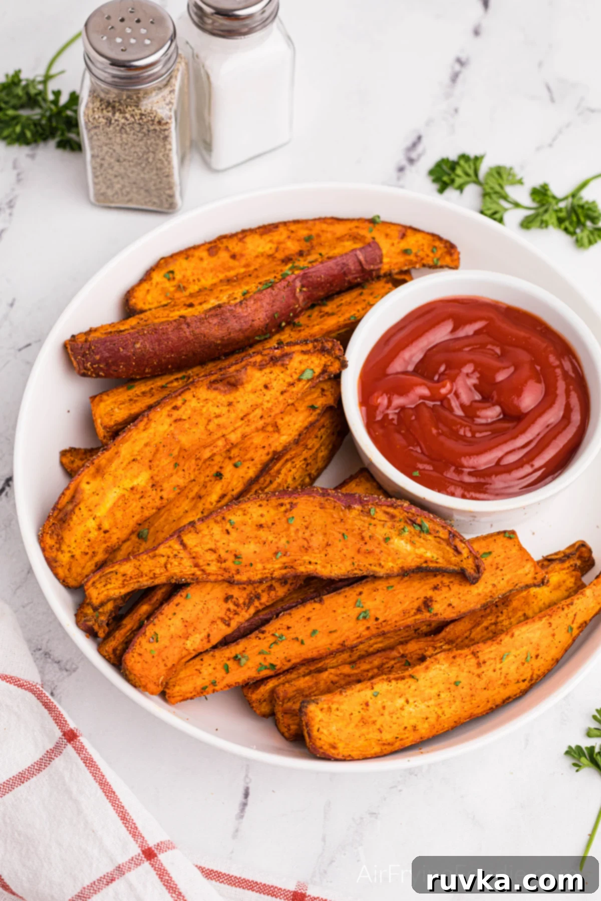 Crave-Worthy Crispy Air Fryer Sweet Potato Wedges 2 Overhead photo of air fried sweet potato wedges with a small bowl of ketchup, on a white plate, ready to serve.