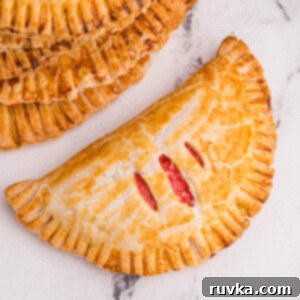 Air Fried Cherry Cream Cheese Pies 12 A single golden-brown cream cheese cherry pie on a white marble countertop, ready to be enjoyed.