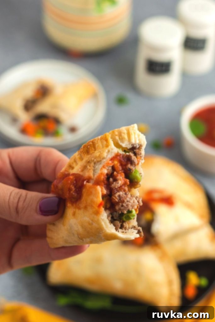 Crispy Air Fryer Empanadas 11 Golden beef empanada broken open with meat and veggies being held by a hand