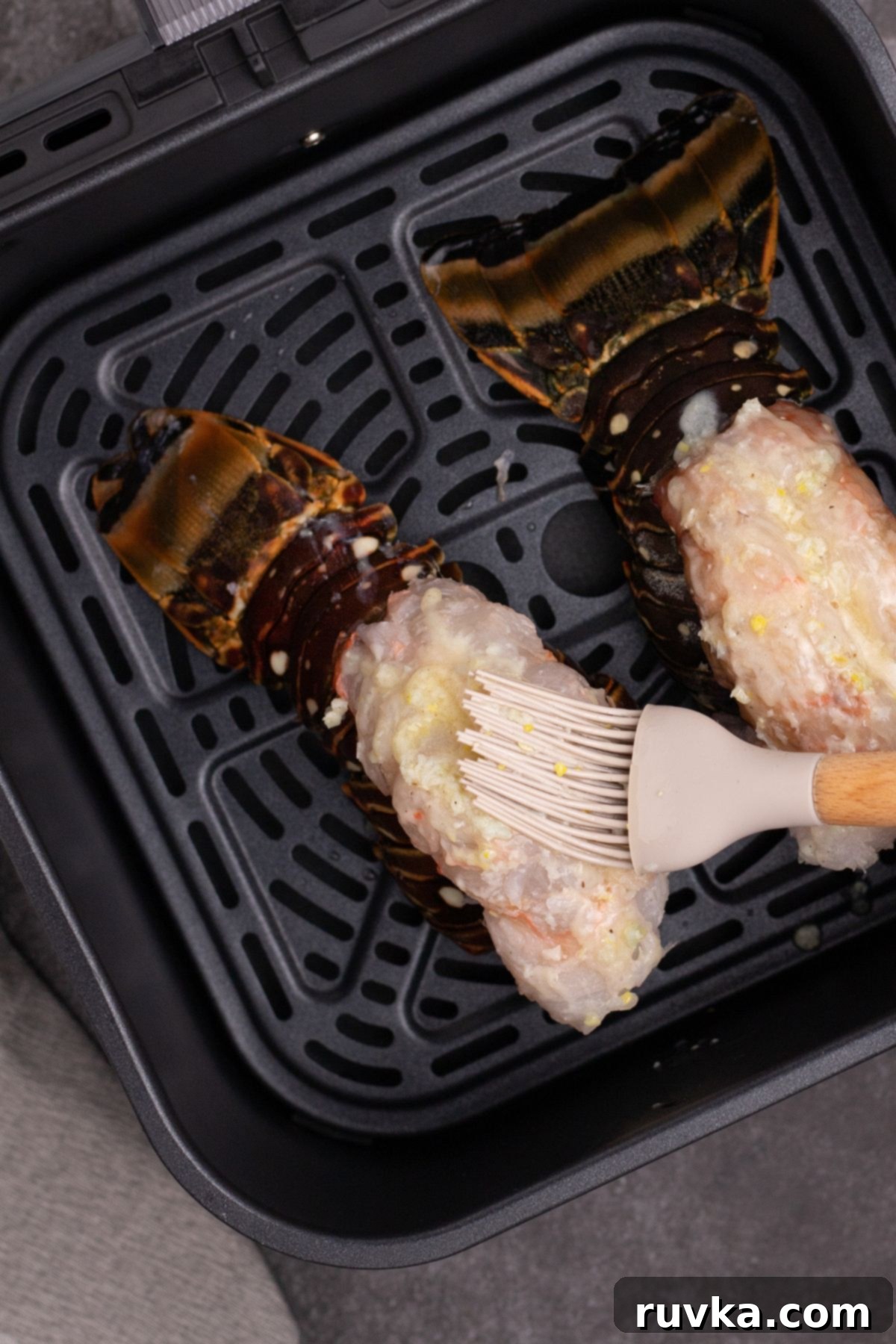 Crispy Air-Fried Lobster Tails 6 Lobster tails in an air fryer basket being brushed with melted butter and seasonings. Two lobster tails nestled in an air fryer basket, being generously brushed with a savory garlic butter mixture for maximum flavor.